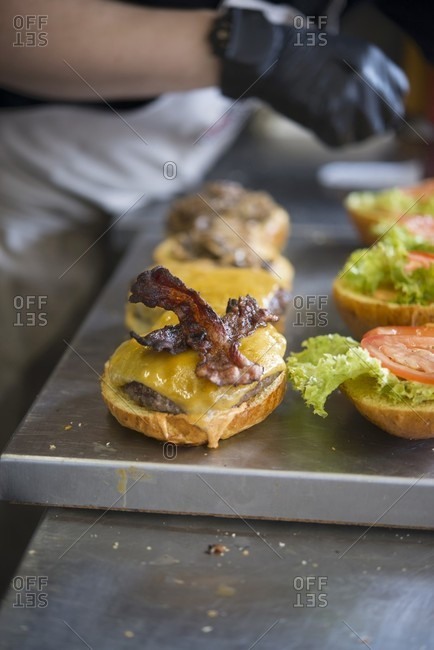 Cheese and bacon burgers being made