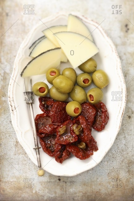 A tapas plater with cheese, olives and dried tomatoes