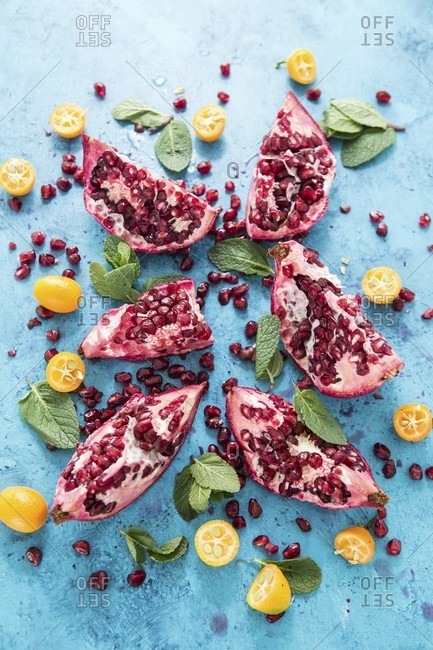 A sliced pomegranate, kumquat and mint leaves