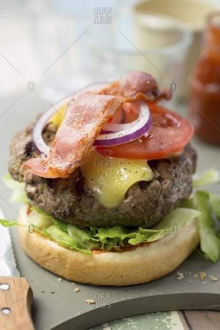 A beef burger with tomatoes and bacon