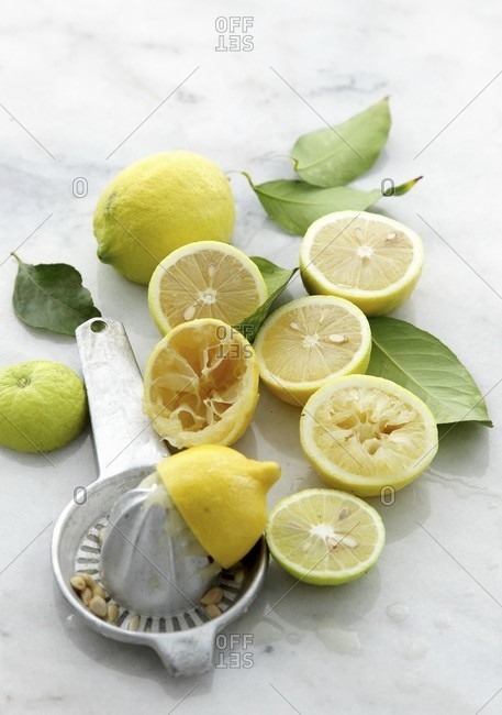 Halved lemons and a lemon juicer on a marble table