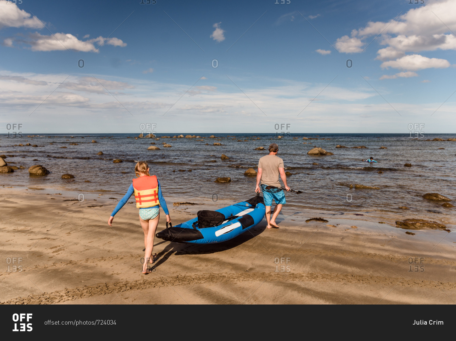 Father and daughter carrying kayak into water, New Zealand