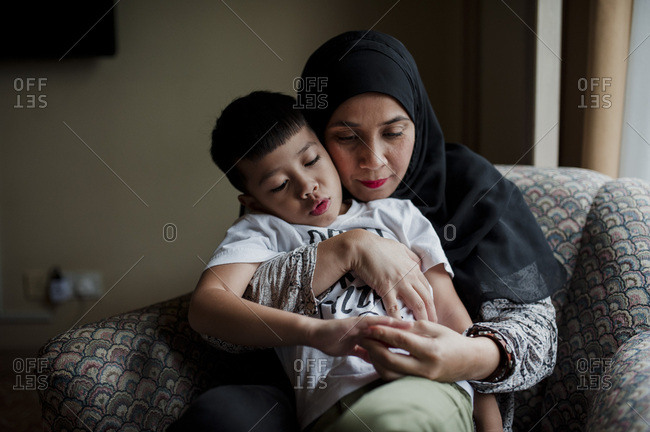 Boy sitting on his mother's lap at home