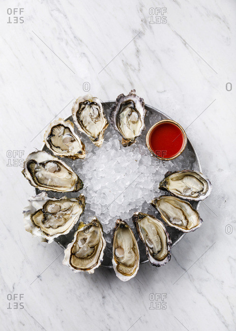 Open Oysters with spicy sauce on white marble background copy space