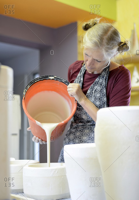 Woman pouring liquid into mold in porcelain workshop