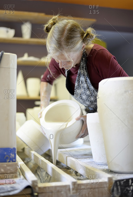 Woman pouring liquid into mold in porcelain workshop