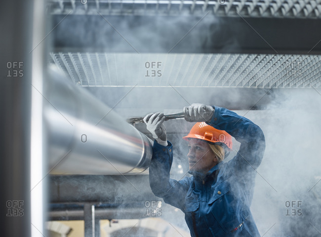 Female mechanic fixing pipework with gaspipe pliers