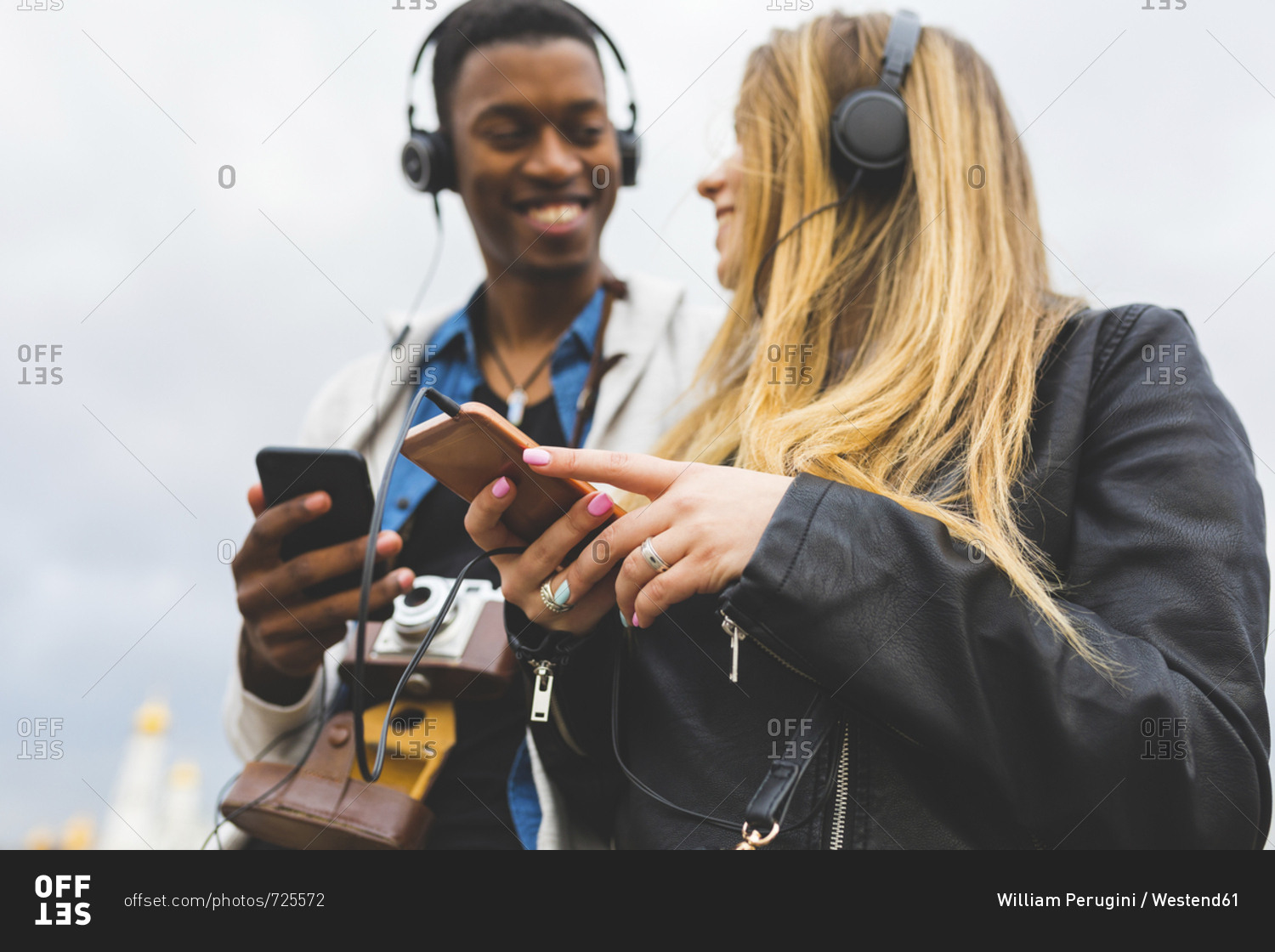 Russia, Moscow, multiracial best friends listening music with headphones