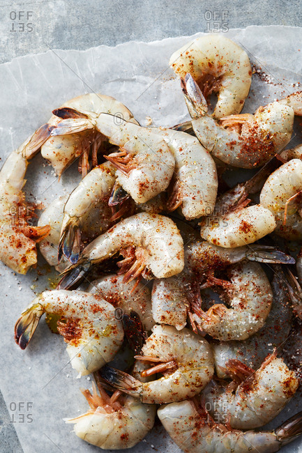 Uncooked shrimp with dry seasonings on parchment paper