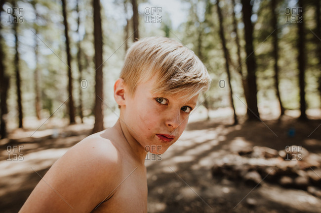 Blonde boy with dirty face in the woods