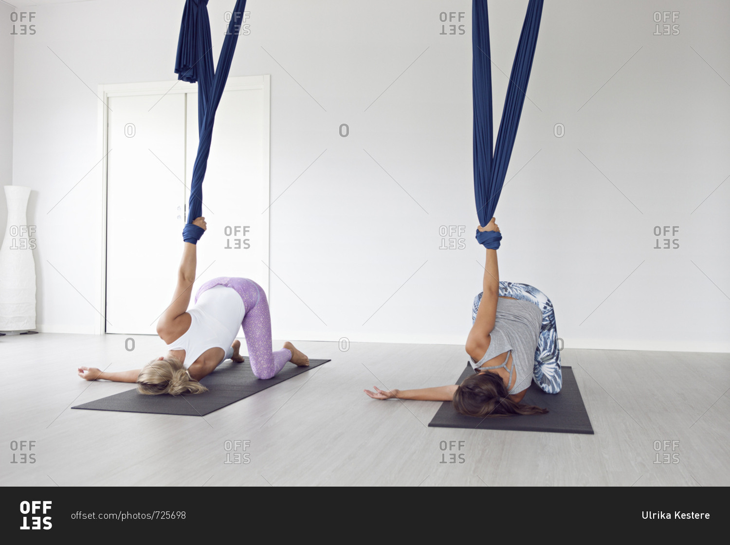 Women using yoga mats and aerial yoga strap