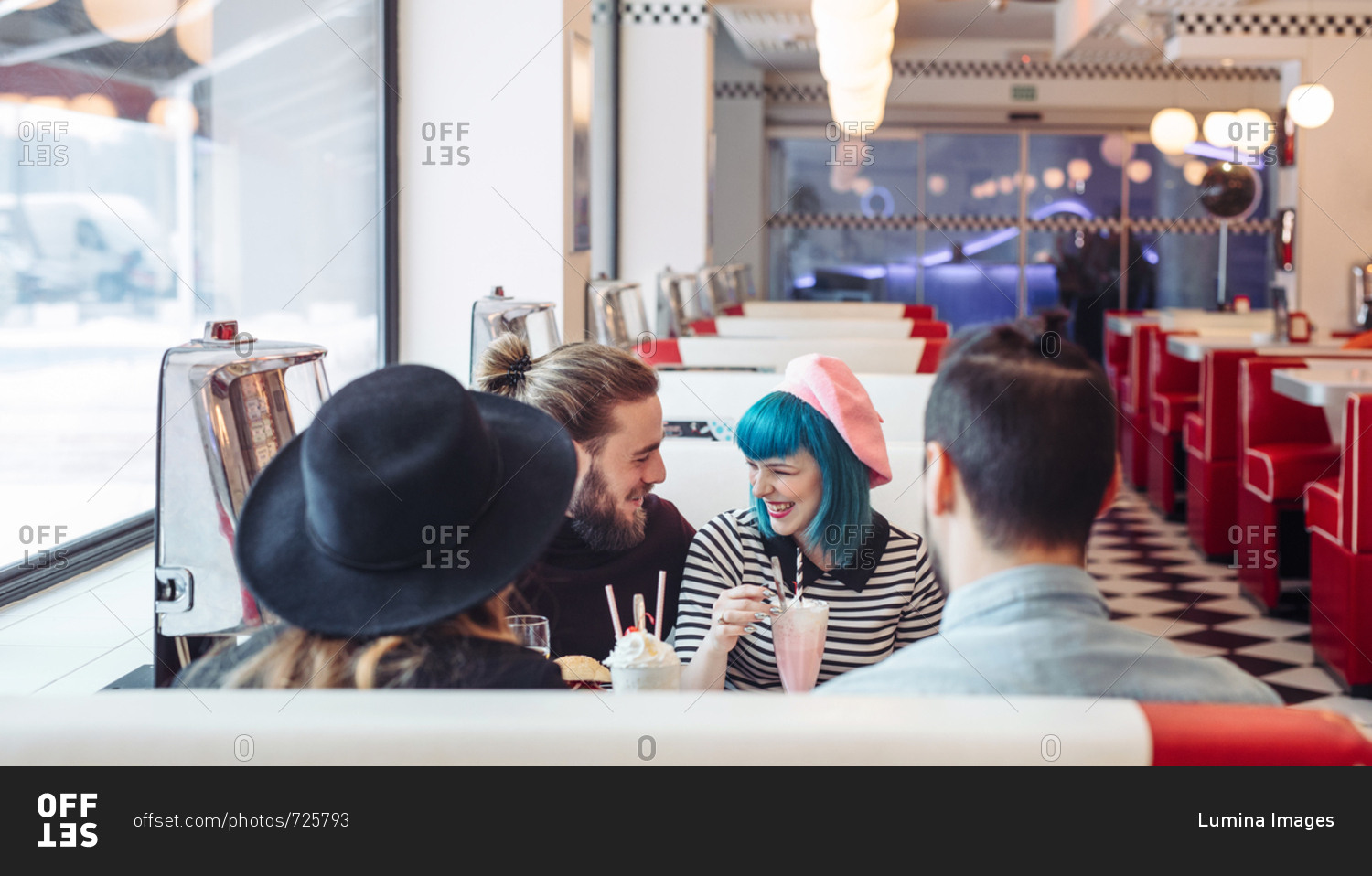 Young stylish men and women laughing at vintage diner restaurant