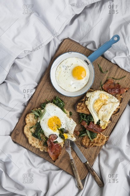 A hearty breakfast with fresh waffles, spinach, bacon and fried eggs