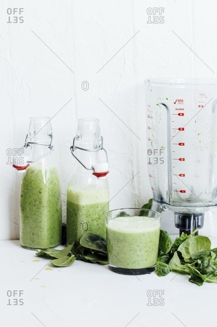 Green smoothies, spinach leaves and a blender