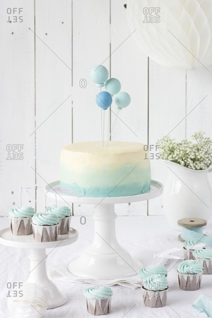An ombre cake with balloons and chocolate cupcakes