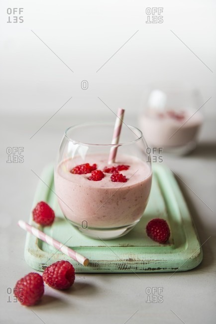 A glass of raspberry drinking yoghurt with fresh raspberries