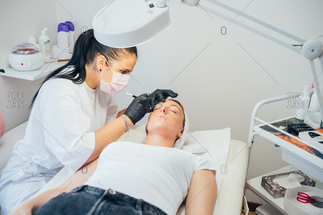 Beautician removing facial hair on a customer - spa treatment, facial hair, epilation concept