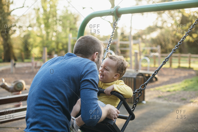 Father And Son Play On Swing In Playground At Sunset Stock Photo Offset