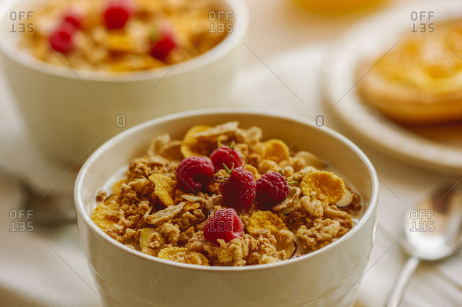Bowl of vanilla almond clusters cereal topped with fresh raspberries