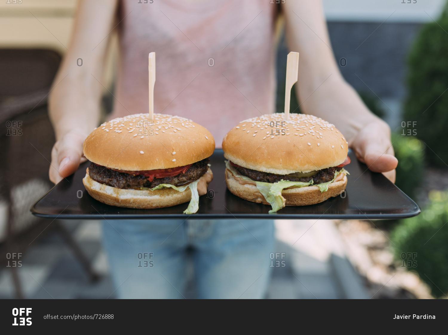 Person serving two hamburgers on tray