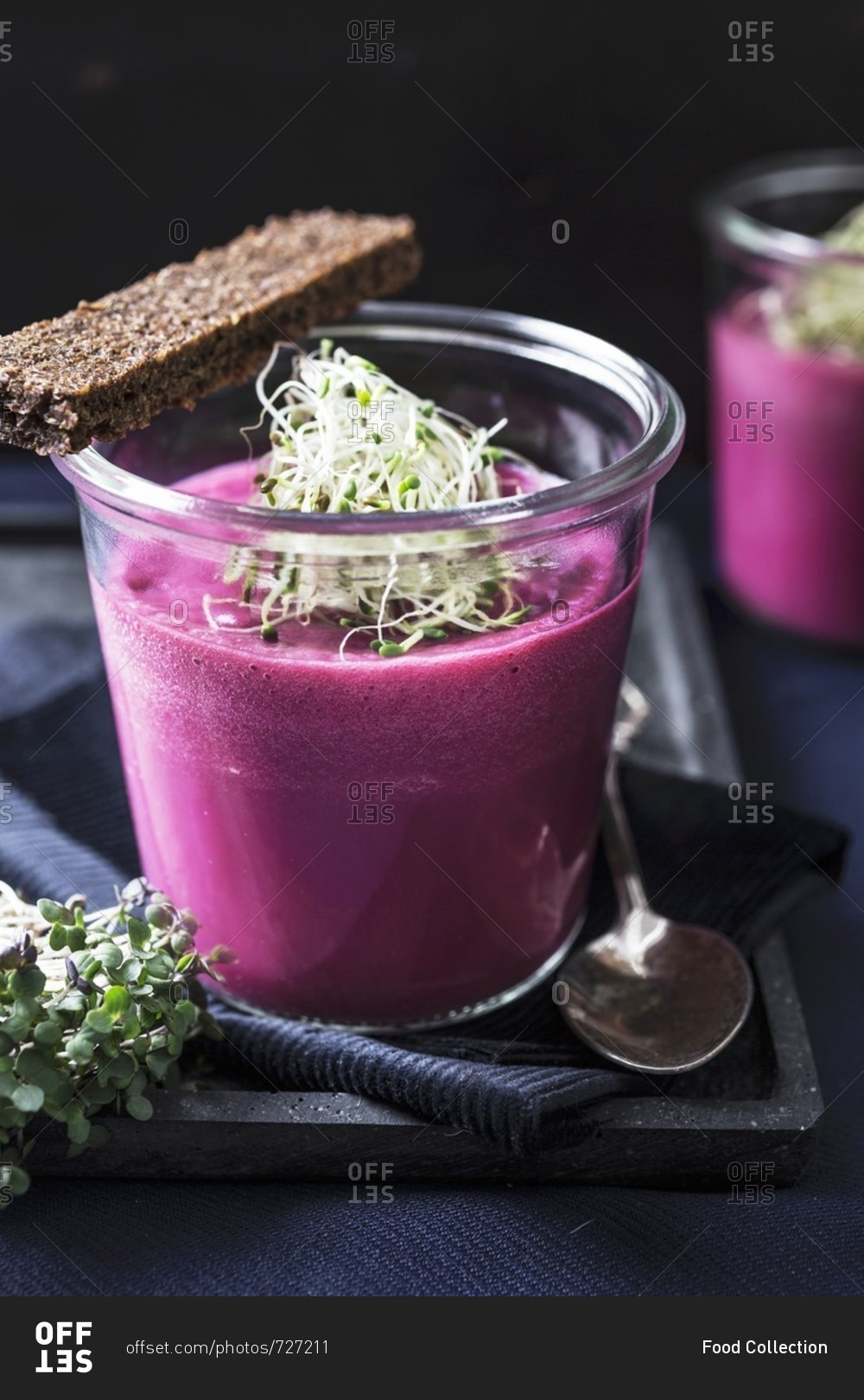 Beetroot and apple soup in a glass with onions and shoots, served with pumpernickel bread and mustard cress