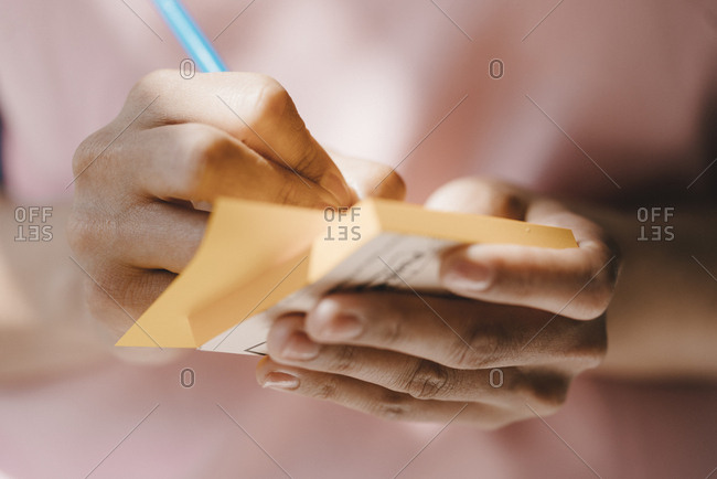 Woman writing with pen on adhesive notes