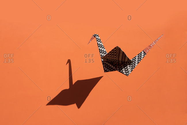 Origami crane- orange background- shadow- copy space