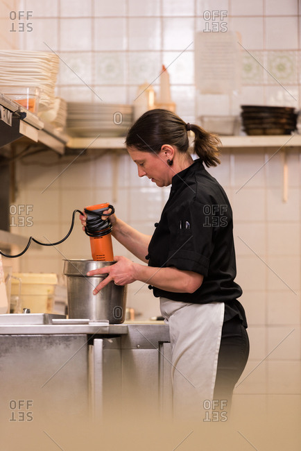 Chef blending with hand blender in the commercial kitchen