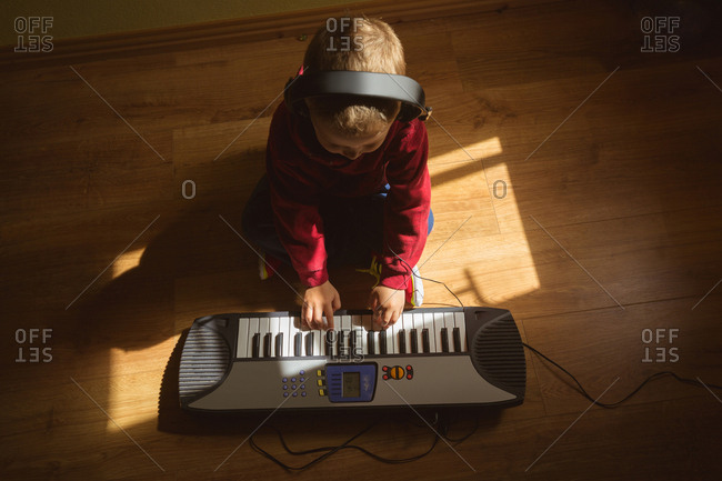 Little boy playing piano in bedroom at home