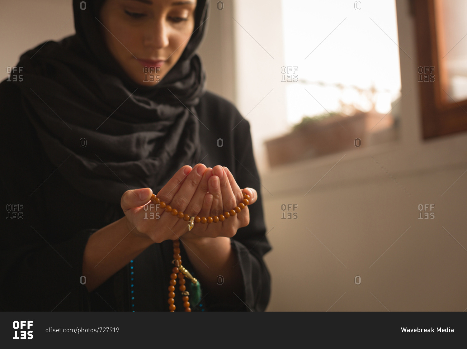 Close-up of muslim woman with prayer beads praying at home