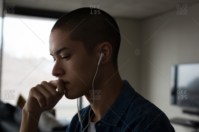 Young man listening music on earphones at home