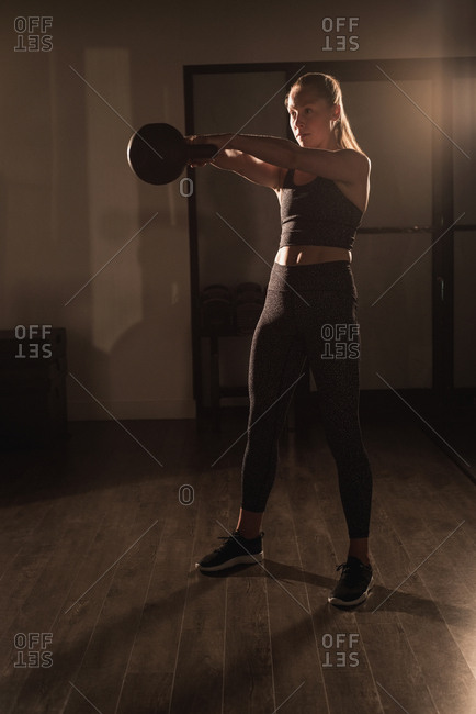 Woman doing exercises with kettlebell in gym