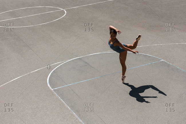 Young female ballet dancer dancing in the basketball court