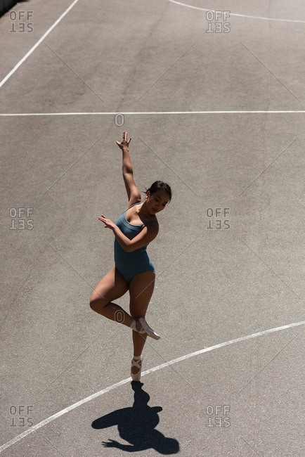 Young female ballet dancer dancing in the basketball court