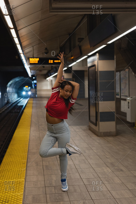 Female street dancer dancing on platform at railway station