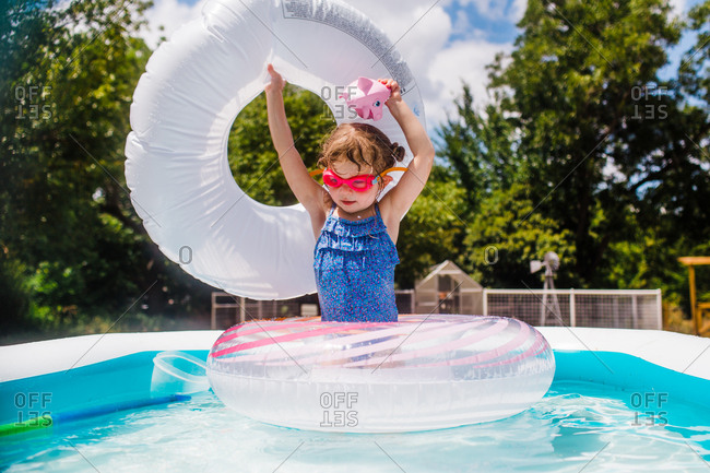 Little Girl In Backyard Pool With Inflatable Rings Stock Photo