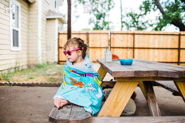 Little girl sitting on picnic table drying off with towel