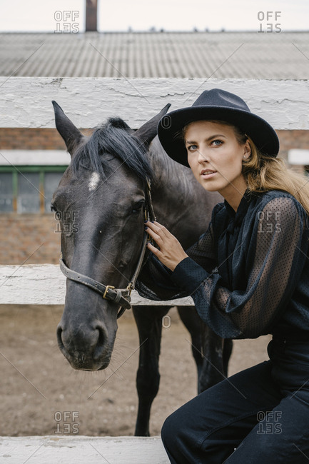 Woman dressed in black beside a black horse