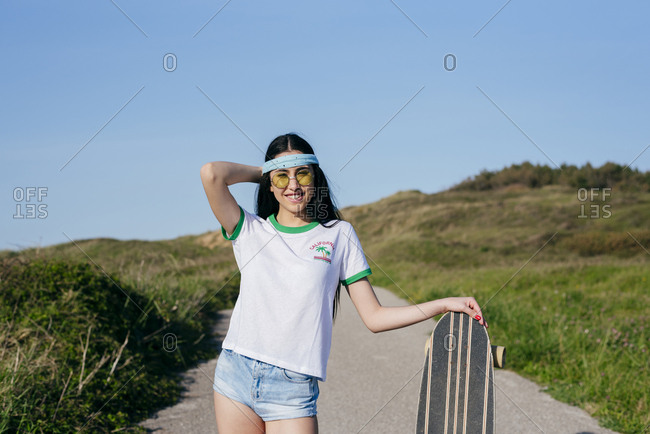 Stylish teen girl with long board in summertime