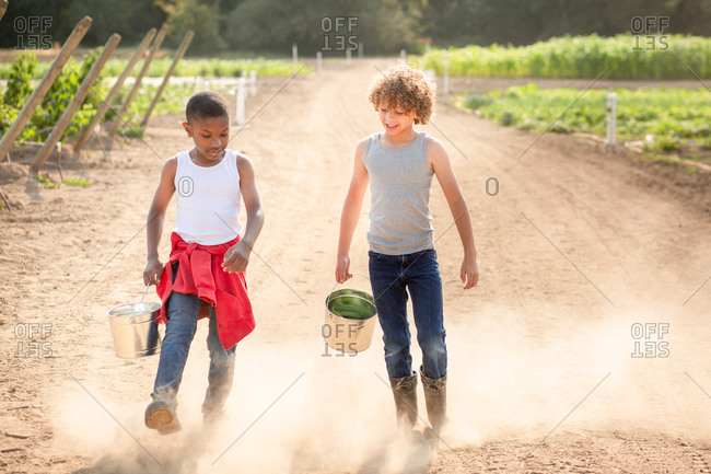 Two brothers walking on dusty path on a farm