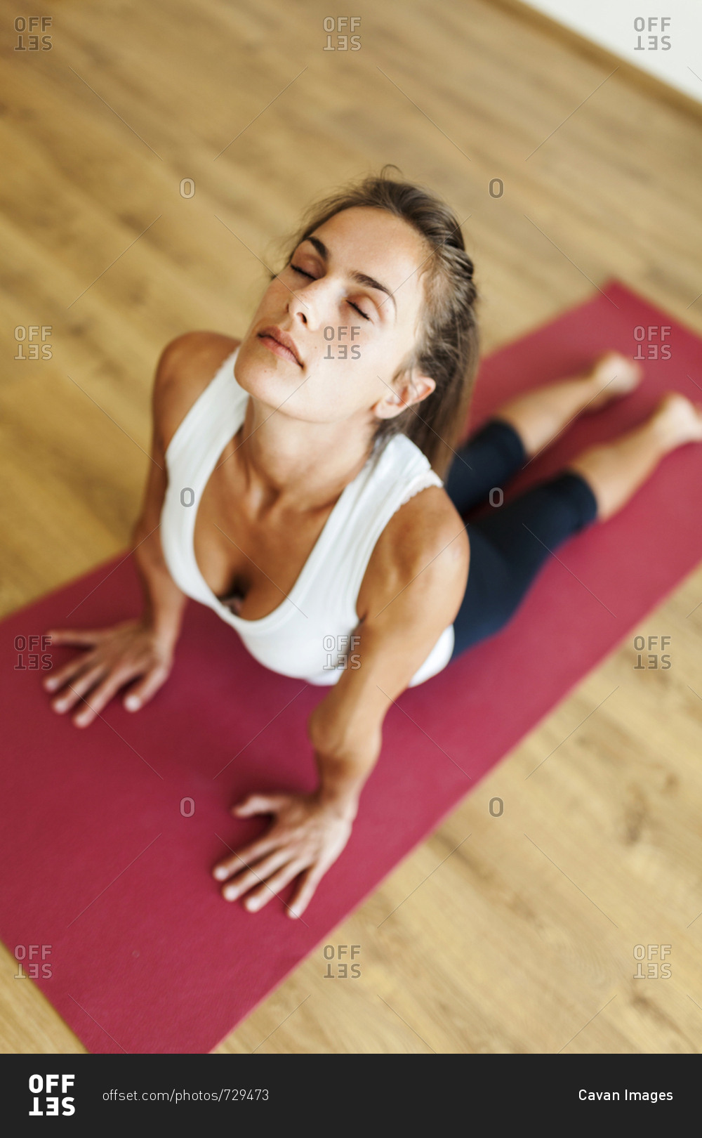 High angle view of woman with eyes closed practicing cobra pose in yoga studio