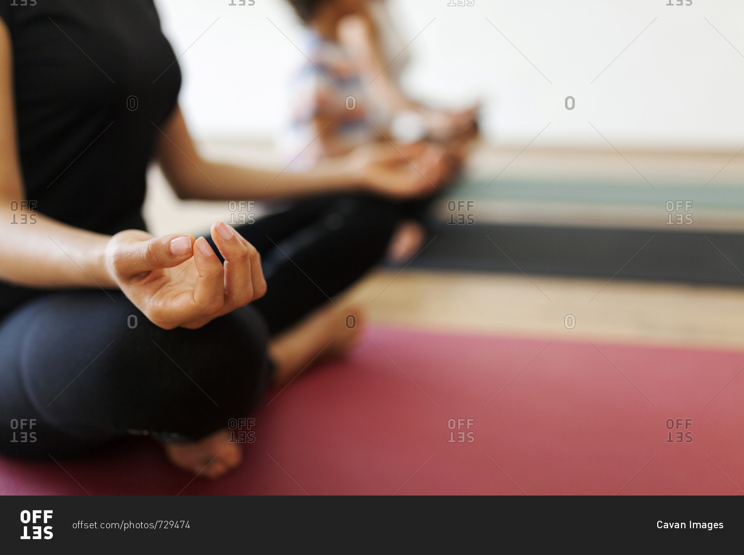Low section of mother and son meditating with female instructor in yoga studio