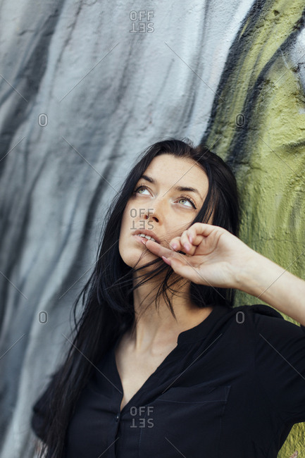 Woman with long dark hair looking up in front of painted mural