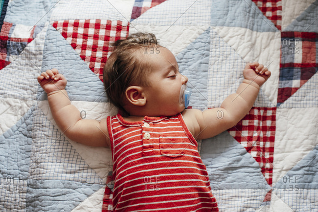 Sleeping baby sprawled out on a quilt