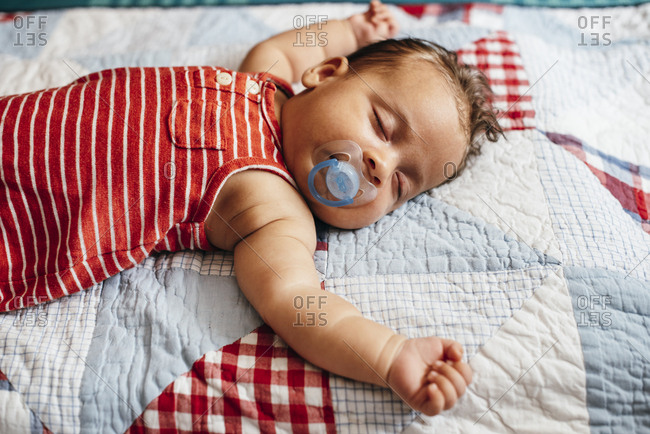 Close up of sleeping baby sprawled out on a quilt