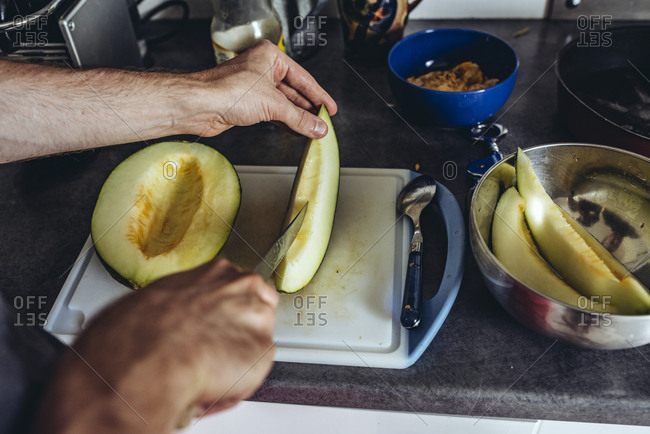 Man cutting melon on cutting board