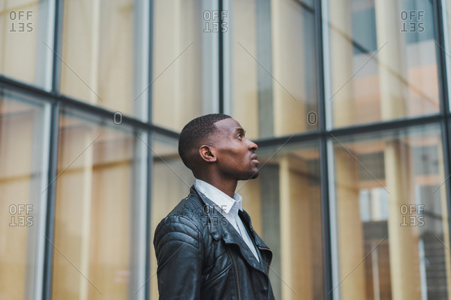 African-American male walking on pavement at building