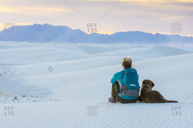 Rear view of woman and dog sitting while hiking in White Sands National Monument, Alamogordo, New Mexico, USA