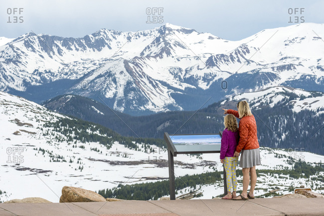 Mother and daughter standing in beautiful natural scenery with snowcapped mountains at Trailridge Road looking at Never Summer Range, Rocky Mountain National Park, Estes Park, Colorado, USA