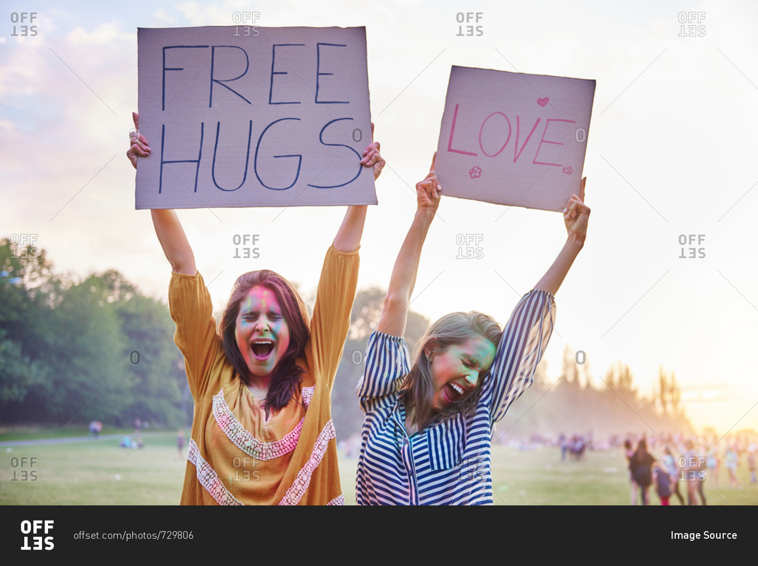 Young women dancing holding up love and free hug signs at Holi Festival